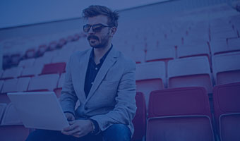 Student des Sport- und Eventmanagements sitzt mit Laptop im Stadion